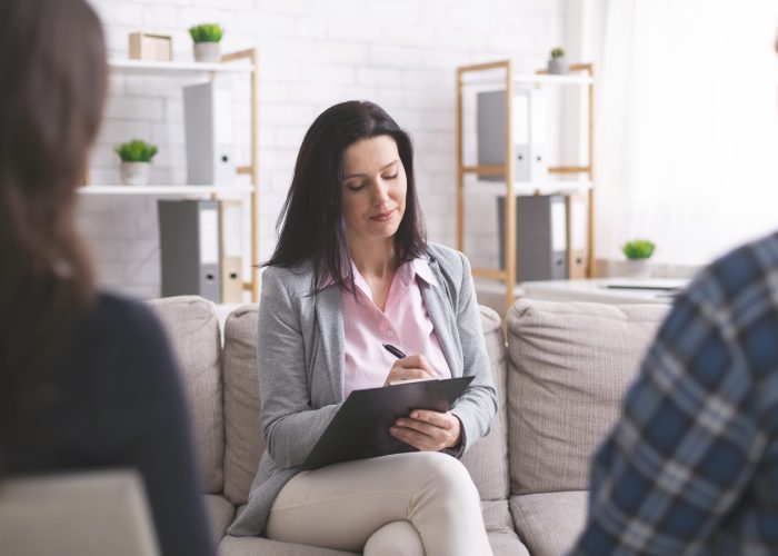 Family therapy. Professional psychologist taking notes at couple meeting with patients