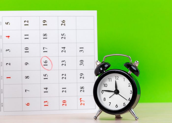 Alarm Clock with Calendar Pages on green background