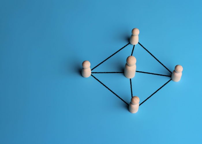 Wooden dolls connected by lines with copy space. Leadership, support, teamwork, networking concept